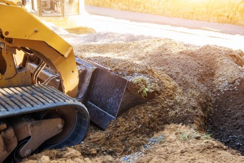 Mini bulldozer working with earth while doing landscaping works on construction moving soil
